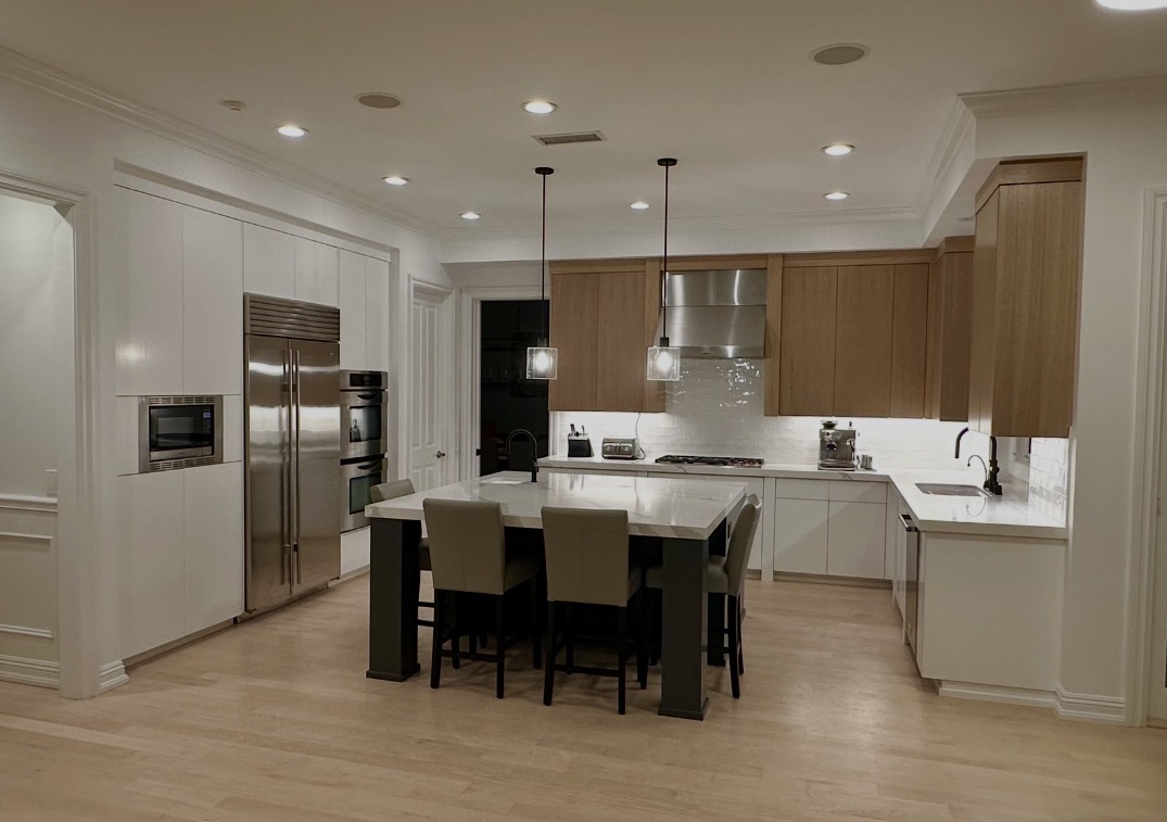Completed kitchen remodel with white cabinetry, oak uppers, marble island, and stainless appliances